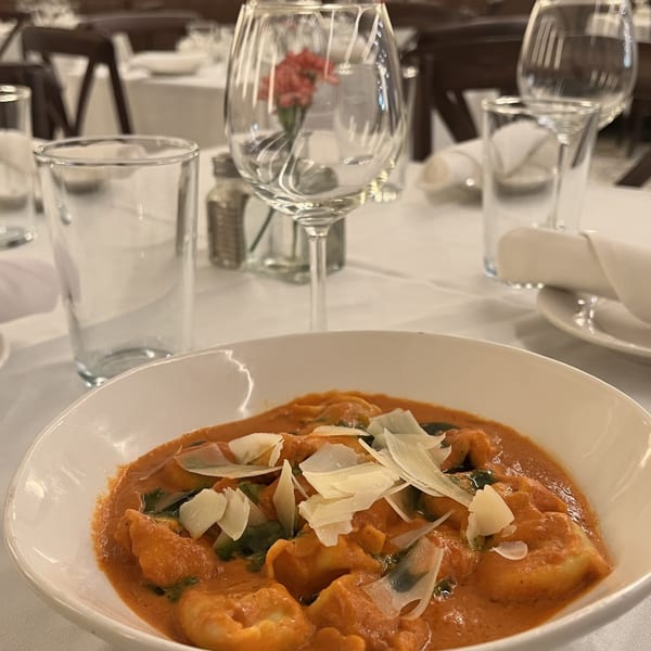 Alba's Pizzeria & Restaurant's ravioli with red sauce and parmesan cheese on a white tablecloth.