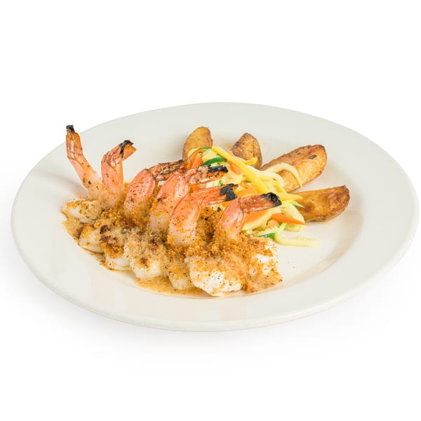 Shrimp scampi with breadcrumbs, potato wedges, and julienned vegetables on a white plate.