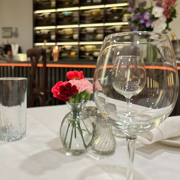 Table setting at Alba's Pizzeria with wine glass, water glass, salt and pepper shakers, and flowers.