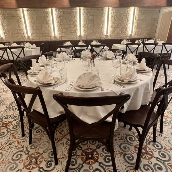 Alba's Pizzeria & Restaurant dining room with set tables, dark chairs, and patterned floor tiles.