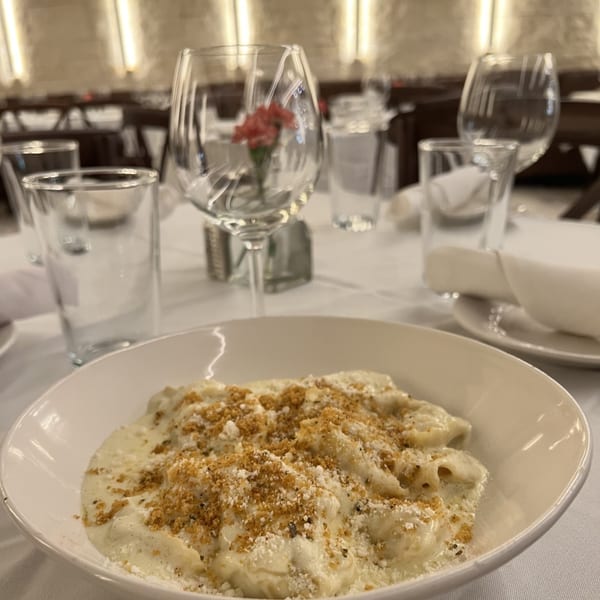 Creamy pasta dish topped with breadcrumbs and cheese, set on a white tablecloth at Alba's Pizzeria.