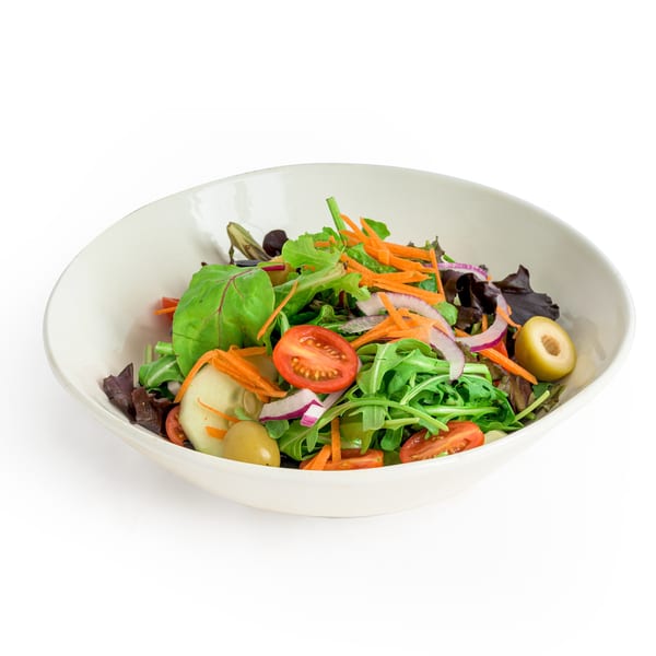 Fresh garden salad with mixed greens, tomatoes, carrots, red onion, and olives in a white bowl.